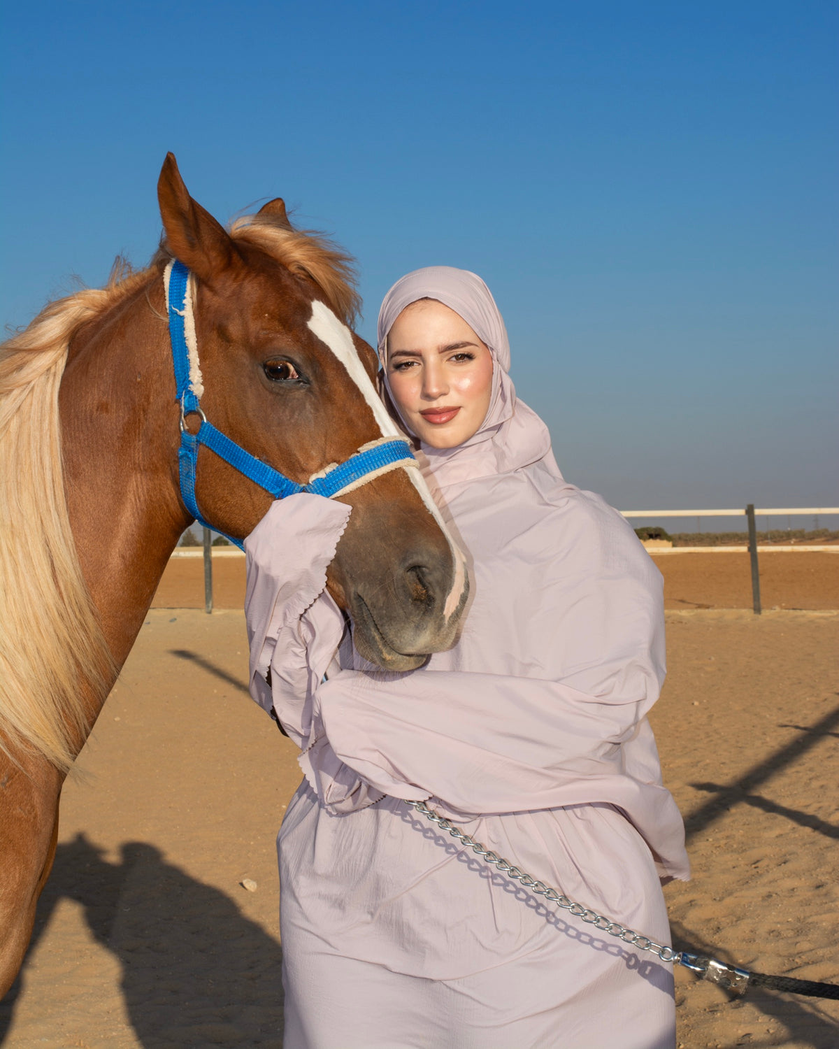 Woman in a prayer garment beside a horse while traveling